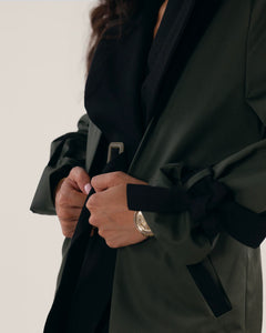 Black and olive green classic trench coat with wide lapels, tortoise shell buttons, welt pockets and hidden detachable belt.