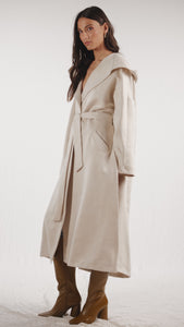 Oversized cream cashmere wool coat with shawl collar that leads to an oversized hood and detachable belt on the waist