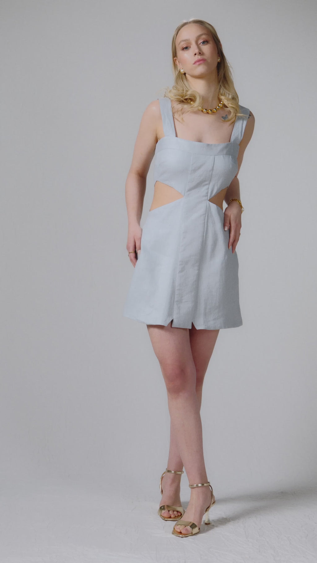 Mini length baby blue linen dress with square neckline and asymmetric cut out details