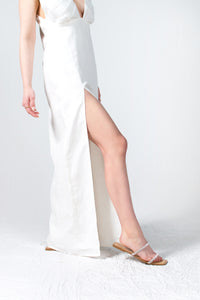 White linen maxi dress with gathered details on the bodice and a side slit